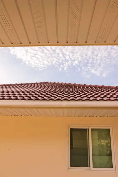 Takpannor, hängränna och fönster mot blå himmel — Stockfoto