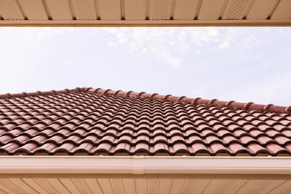 Dachziegel und Regenrinne horizontal gegen blauen Himmel — Stockfoto