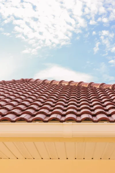 Плитка на крыше, дождевая канава и окна против голубого неба — стоковое фото