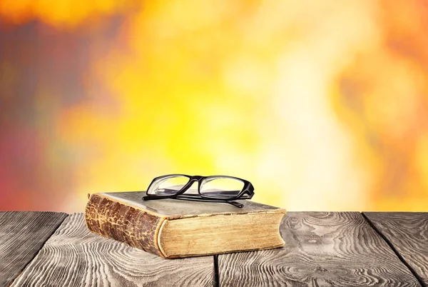 Oud boek met een bril op houten tafel — Stockfoto