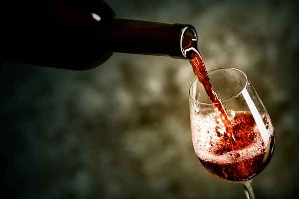 Vinho tinto está sendo derramado no copo — Fotografia de Stock