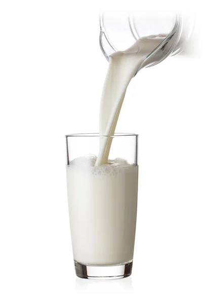 Milk pouring into a glass from glass jug — Stock Photo, Image