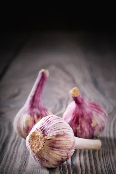 Three heads of garlic on a wooden table — Stock Photo, Image