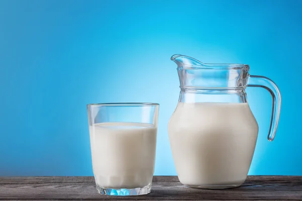 Milk in a glass and jug on a wooden table — Stock Photo, Image
