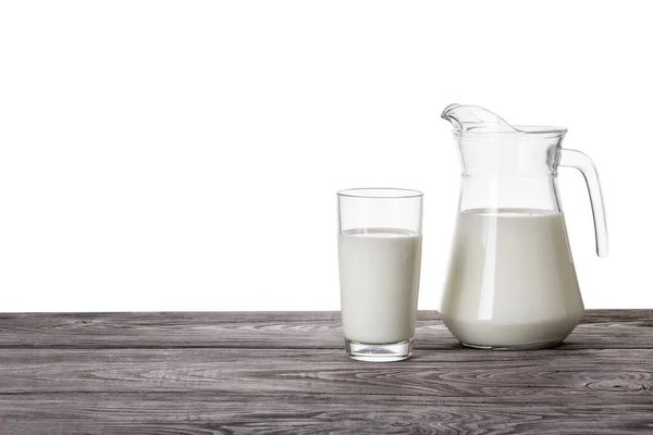 Jug and a glass of milk on a wooden table — Stock Photo, Image