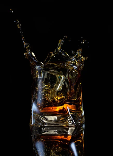 Splash van whisky in vierkante glas — Stockfoto
