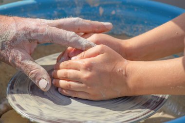 Çömlekçinin elleri ve çocuk kille çalışır.