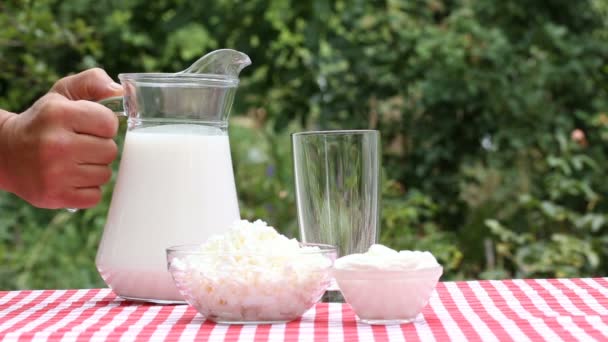 Ruka nalévá mléko ze džbánu do skla — Stock video