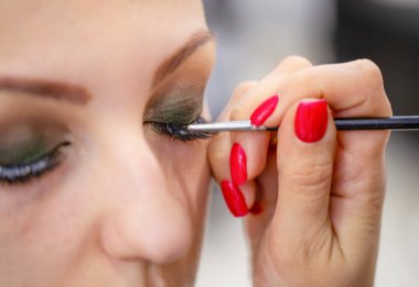 Girl make up eyelashes in beauty salon