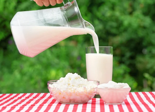 Milk pouring from a jug into a glass — Stock Photo, Image