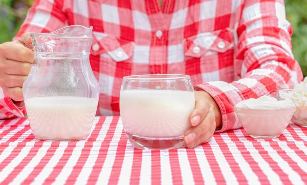 Woman in red shirt holds out glass of milk — Stock Photo, Image