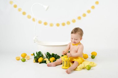  Limonlu ve limonlu süt banyosu yapan sevimli bebek. Beyaz arka planda limon yiyen çocuk.