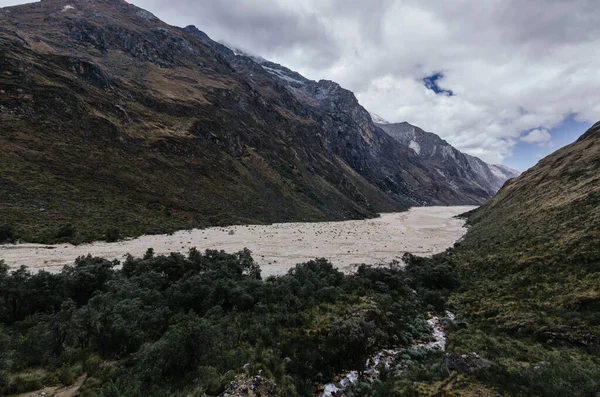 Peru 'daki dağların arasındaki Santa Cruz geçidinde, bitki örtüsünün yanındaki vadide bir çığ kalıntısı.
