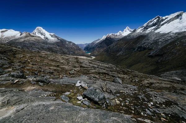 Quebrada Santa Cruz 'daki kayalık vadide yüksek karlı dağlar ve Peru' nun arka planında buzul gölleri var.