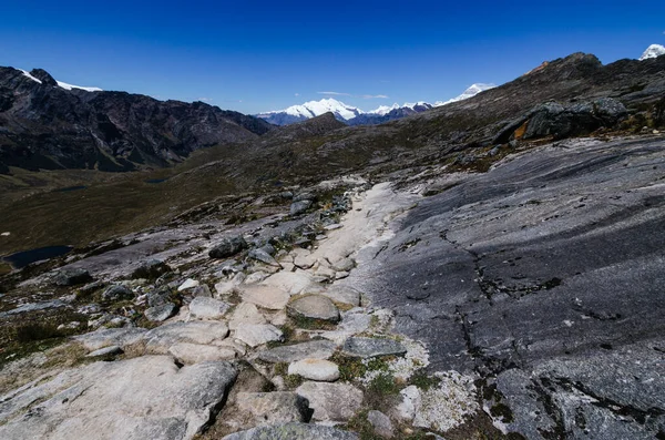 Punta Union yakınlarındaki kayalık patika peru 'daki quebrada santa cruz yürüyüşünde arka planda karlı dağ pucaraju ile