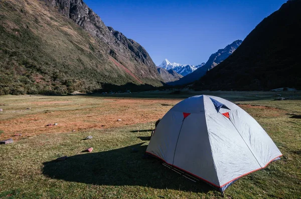 Arka planda yüksek karlı dağlar olan gri kamp çadırı, Peru 'daki quebrada santa cruz yürüyüşü