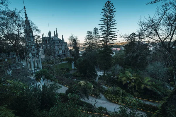 Sintra, Portekiz, 25 Ocak 2020: Quinta da regaleira bahçeli saray ve şapel gün batımında bitki örtüsü arasında