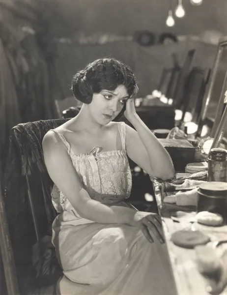 Mulher sentada à mesa de vestir — Fotografia de Stock