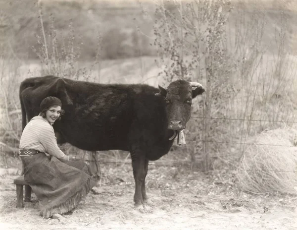 Frau sitzt neben Kuh — Stockfoto