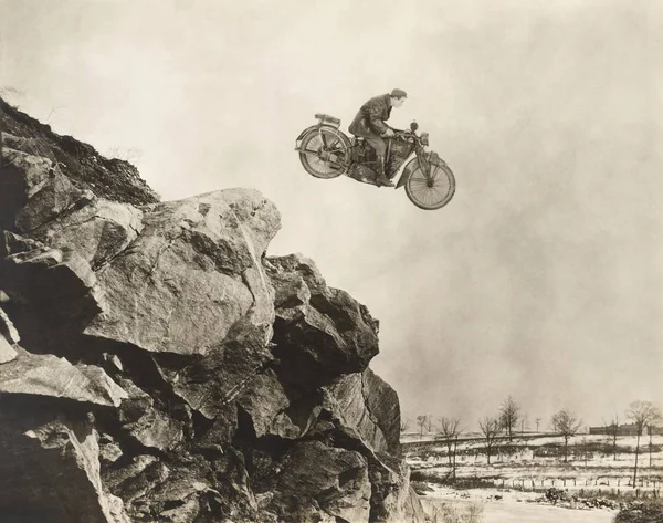 Человек на мотоцикле прыгает со скал — стоковое фото