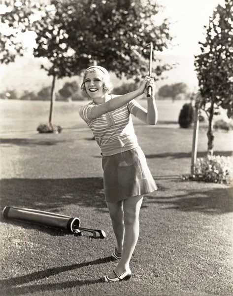 Frau schwingt Golfschläger Stockbild