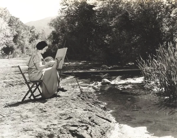 Woman painting by river — Stock Photo, Image