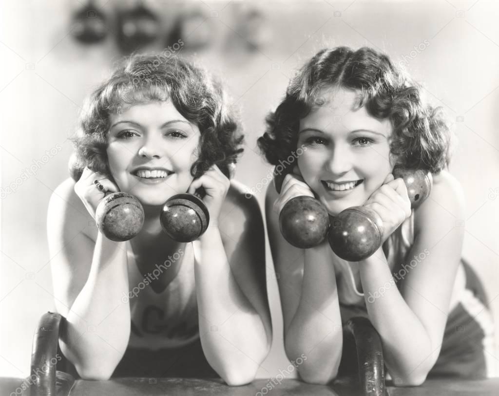 women smiling while holding dumbbells