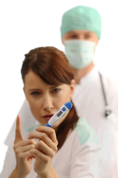 Αυστηρή Νοσοκόμα Δείχνει Θερμόμετρο Γιατρός Πίσω — Φωτογραφία Αρχείου