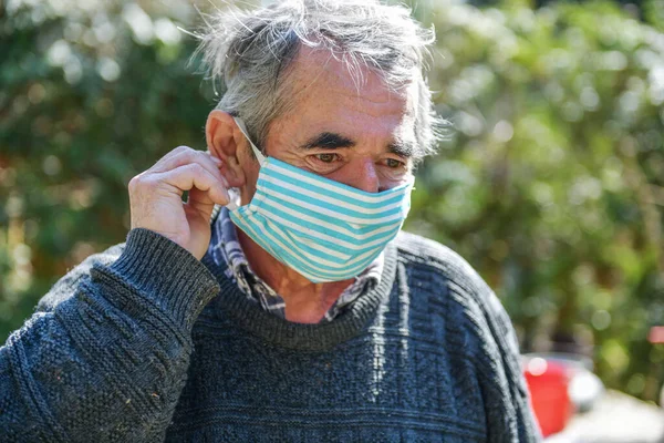 Portrait of an old man, 75 years old, in a medical mask. A concept of the danger of coronavirus for the elderly.