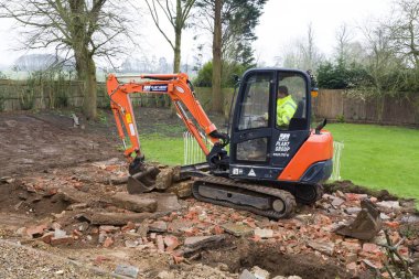 BUCKINGHAM, İngiltere - 13 Şubat 2016. Kazıcı, buldozer enkazı temizliyor. Birleşik Krallık 'ta bir bahçe düzenlemeye hazırlanıyor.