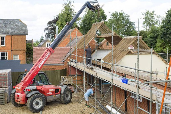 BUCKINGHAM, UK - September 08, 2016. Builders working with a telehandler for demolition and rebuild restoration of a house in Buckinghamshire, UK