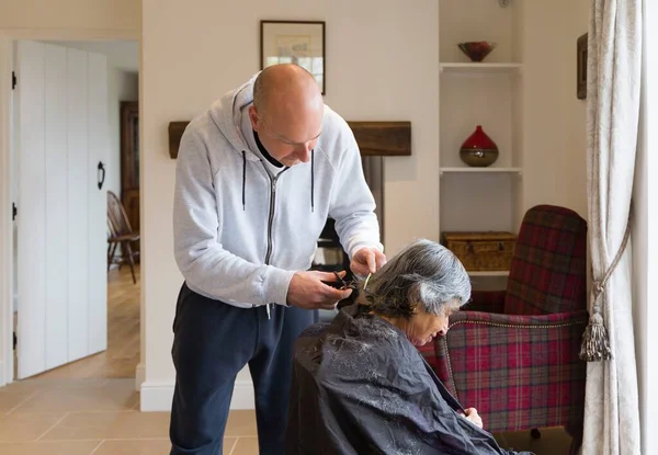 Old elderly woman having a haircut at home during coronavirus, UK