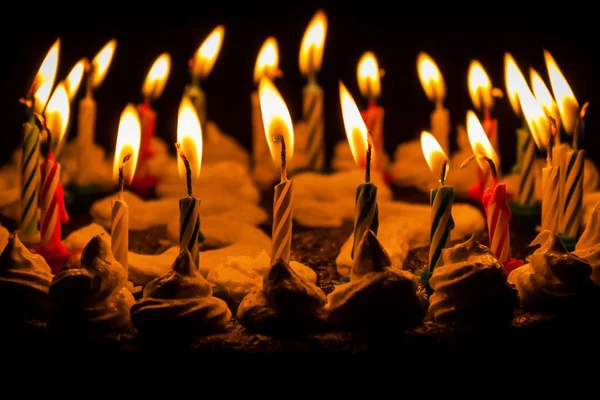 Siyah arkaplanda yanan mumlarla doğum günü pastası.