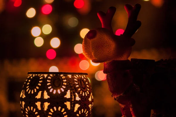 Noel geyiği figürü. Arka planda mumlar ve ışık var.