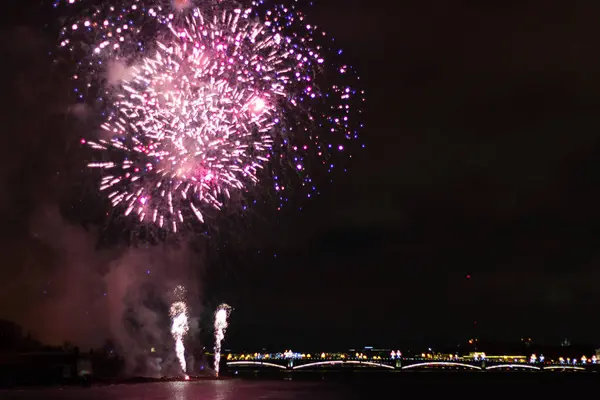 Fogos de artifício sobre a cidade luzes rosa e roxas — Fotografia de Stock