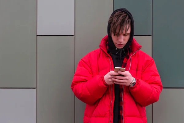 Young hipster holding the phone and hangs out in social networks — Stock Photo, Image