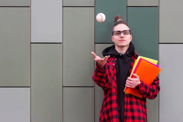 Student trzymać książki rzuca piłkę patrząc w kamerę — Zdjęcie stockowe