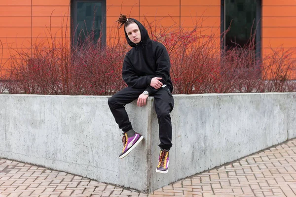 Trendy stylish guy sitting on the railing.street fashion — Stock Photo, Image