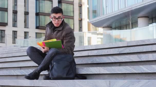 Genç Asyalı Erkek Öğrenci Üniversitenin Merdivenlerinde Oturuyor Kitap Okuyor — Stok video