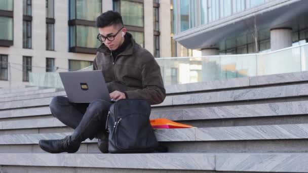 若い成功したアジアの学生プログラマーはラップトップフリーのオフィスビルの階段に座って — ストック動画