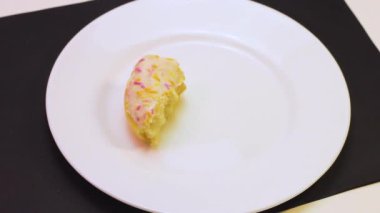 Bir yarısı yenmiş donut kahvaltısı tabağın arkasında tatlı.