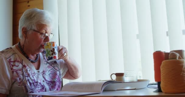 Seniorin Liest Buch Und Trinkt Kaffee Der Werkstatt — Stockvideo