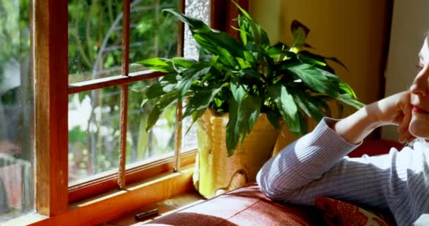 Przemyślane Starsza Kobieta Patrząc Przez Okno Domu — Wideo stockowe