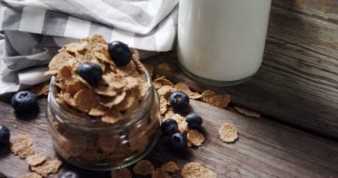 Buğday gevreği ve ahşap masa 4 k üzerinde yaban mersini kavanoz dolu