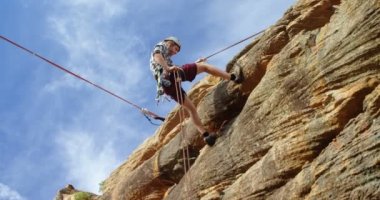 Güneşli bir günde 4 k dağdan aşağı rappelling dağcı