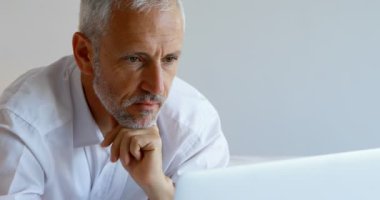 Olgun işadamı 4 k otel odasında dizüstü bilgisayar kullanarak