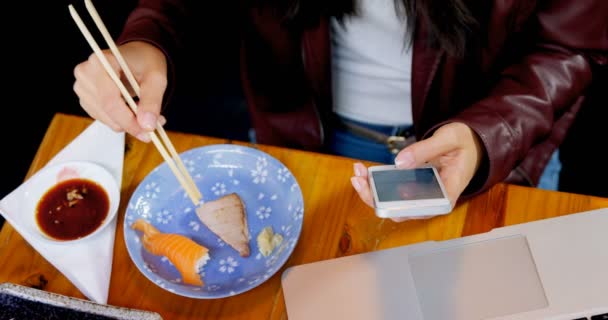 Sección Media Mujer Que Tiene Sushi Mientras Usa Teléfono Móvil — Vídeos de Stock