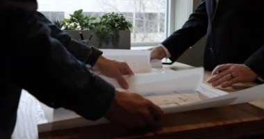 Karışık ırktan bir kadın mimar ve iki beyaz erkek mimarın bir ofiste sıradan bir toplantı sırasında birlikte mimari planlara bakmaları, birinin onları sarıp dışarı çıkarması.