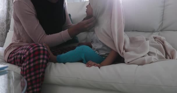 一个年轻的混血儿和她的小女儿在客厅里戴头巾 坐在沙发上 一起玩耍 一个女人把头巾放在她女儿的头上 — 图库视频影像