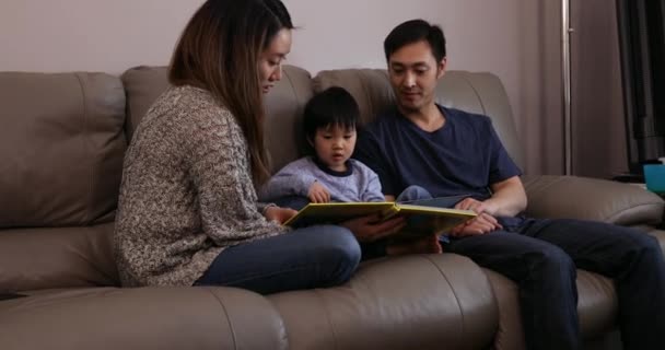 ソファに座って本を持っている息子と彼の両親と読書をしています — ストック動画